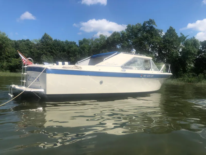 Slide: The Image of 1968 Chris-Craft COMMANDER 27 boat on calm water, surrounded by trees and blue sky. - 2