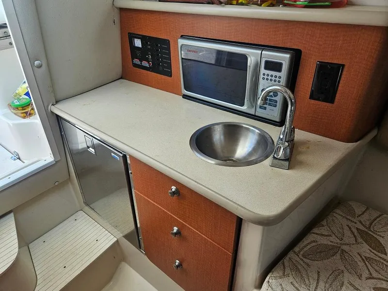 Slide: The Image of 2005 Robalo R265 Walkaround boat interior with kitchenette, sink, and microwave. - 12