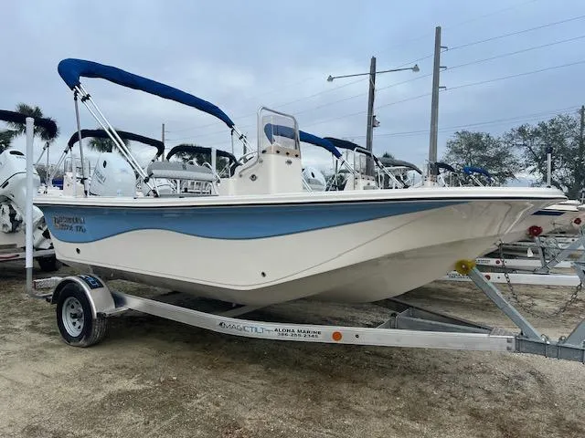 The Image of 2025 Carolina Skiff 17 LS boat on trailer with blue canopy in a marina. - 0