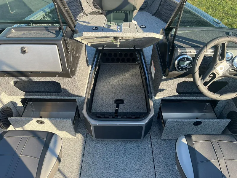 Slide: The Image of 2025 Lund 1775 Impact XS Sport boat interior with open storage compartments and steering wheel. - 10