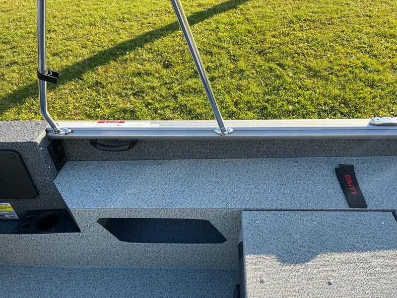 Slide: The Image of 2025 Lund 1775 Impact XS Sport boat interior with gray seating and green grass background. - 25
