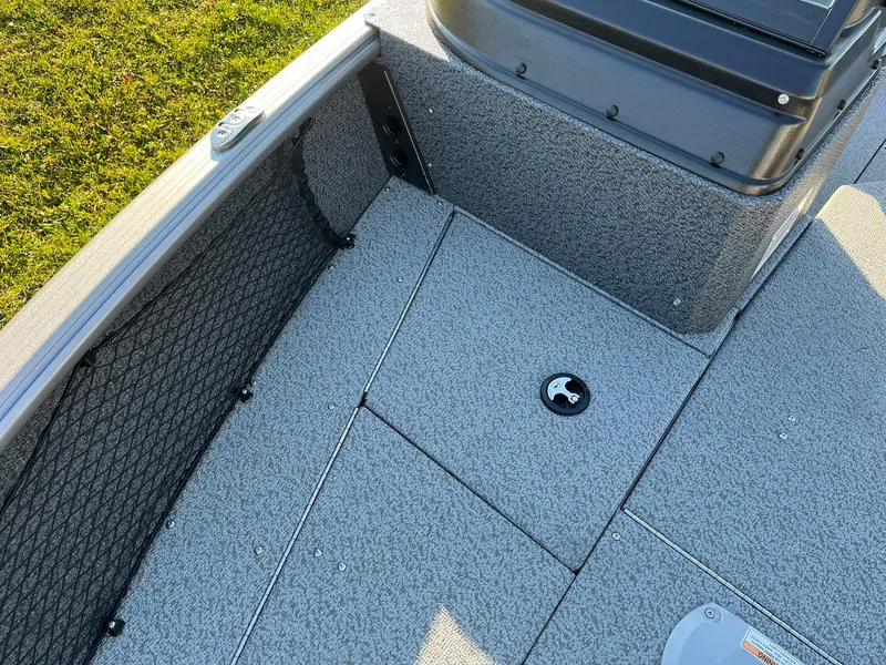 Slide: The Image of 2025 Lund 1775 Impact XS Sport boat interior with gray carpet and storage compartment. - 26