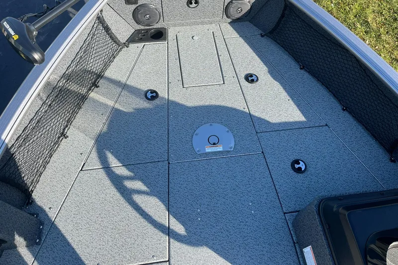 Slide: The Image of 2025 Lund 1775 Impact XS SS boat interior with gray flooring and storage compartments. - 15