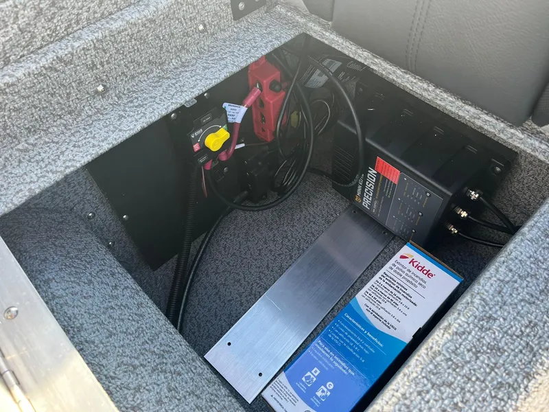 Slide: The Image of 2025 Lund 1775 Impact XS SS boat battery compartment with wiring and charger. - 24