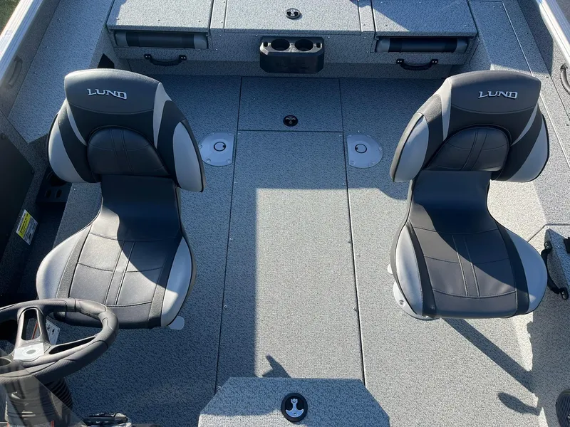 Slide: The Image of 2025 Lund 1775 Impact XS SS boat interior with two black seats and steering wheel. - 7