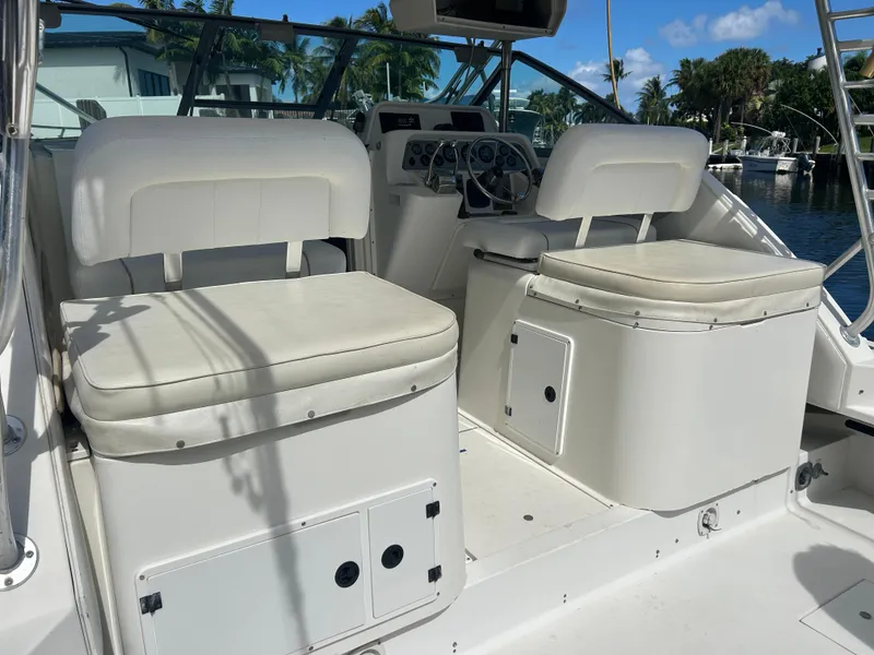 Slide: The Image of 1999 Wellcraft 330 Coastal boat interior with white cushioned seats and steering console. - 10