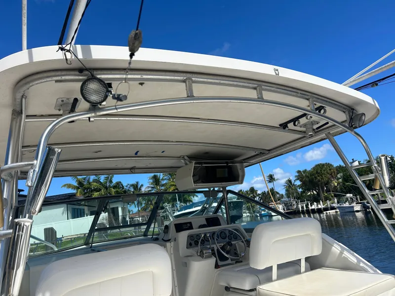 Slide: The Image of 1999 Wellcraft 330 Coastal boat helm with canopy, docked near palm trees. - 12