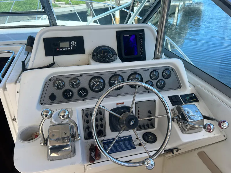 Slide: The Image of 1999 Wellcraft 330 Coastal boat dashboard with steering wheel and control panel. - 16