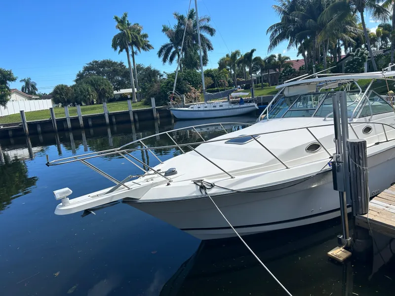 Slide: The Image of 1999 Wellcraft 330 Coastal boat docked in a sunny marina with palm trees. - 3