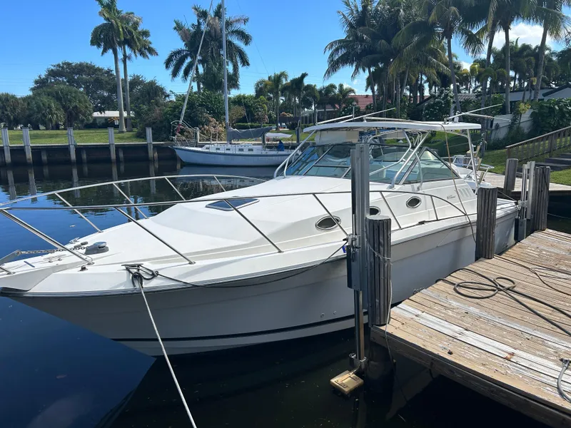 Slide: The Image of 1999 Wellcraft 330 Coastal boat docked by palm trees and calm water. - 4