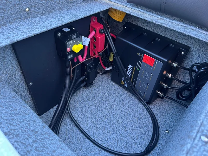 Slide: The Image of 2025 Lund 1875 Impact XS SS boat battery compartment with wiring and charger. - 23