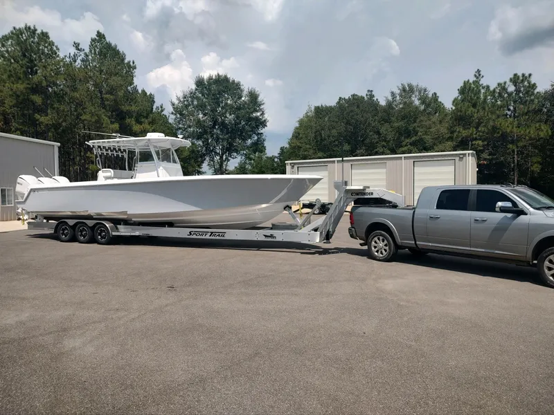 Slide: The Image of 2024 Contender 39 ST boat on trailer, towed by a truck in a parking lot. - 12