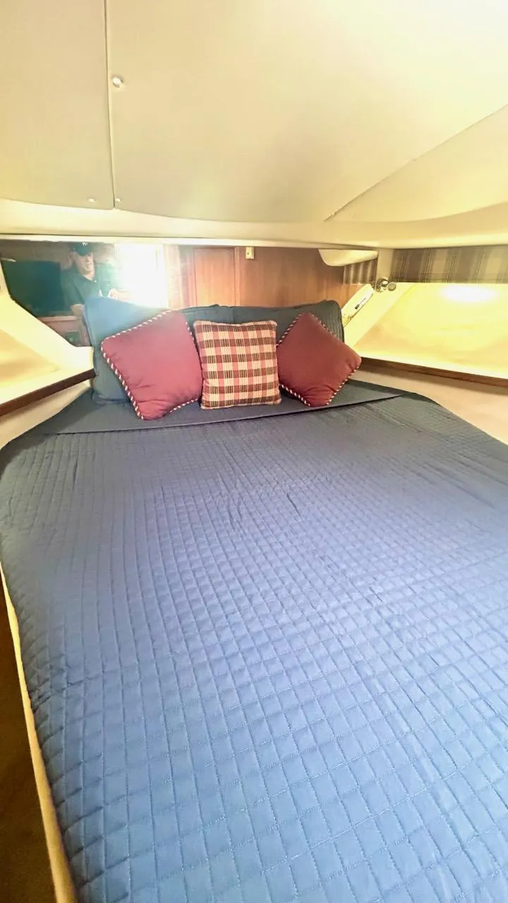 Slide: The Image of 2000 Tiara Yachts 3700 Open cabin with bed, blue bedding, and decorative pillows. - 40