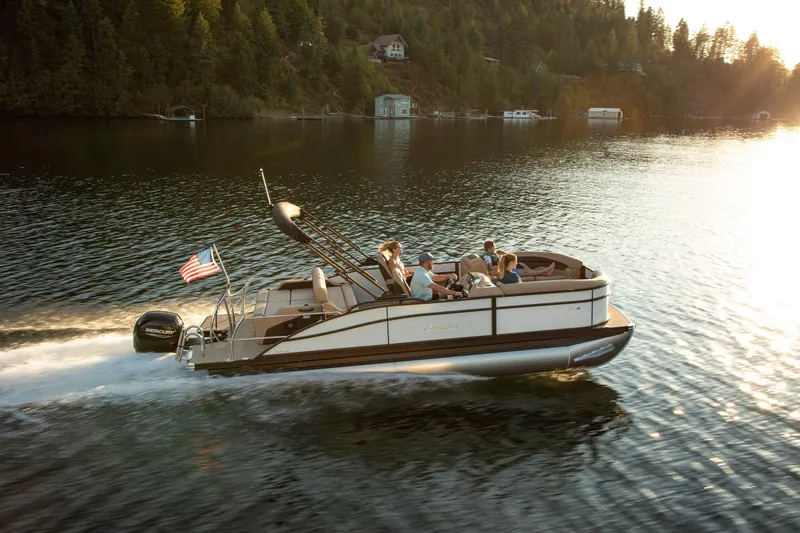 Slide: The Image of 2025 Barletta C22UC pontoon boat cruising on a scenic lake at sunset. - 10