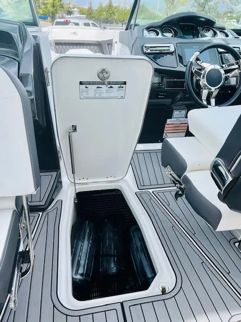 Slide: The Image of 2019 Monterey 298 Super Sport boat interior with open storage compartment and modern dashboard. - 13