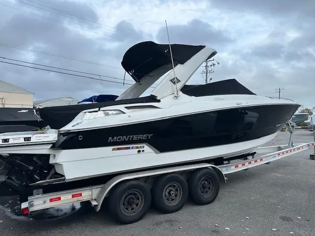 Slide: The Image of 2019 Monterey 298 Super Sport boat on a trailer, black and white design, overcast sky. - 23