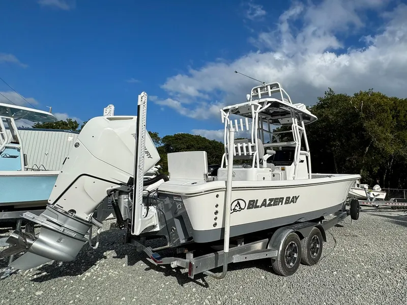 Slide: The Image of 2025 Blazer 2700 Hybrid Bay boat with tower on trailer, parked outdoors. - 1