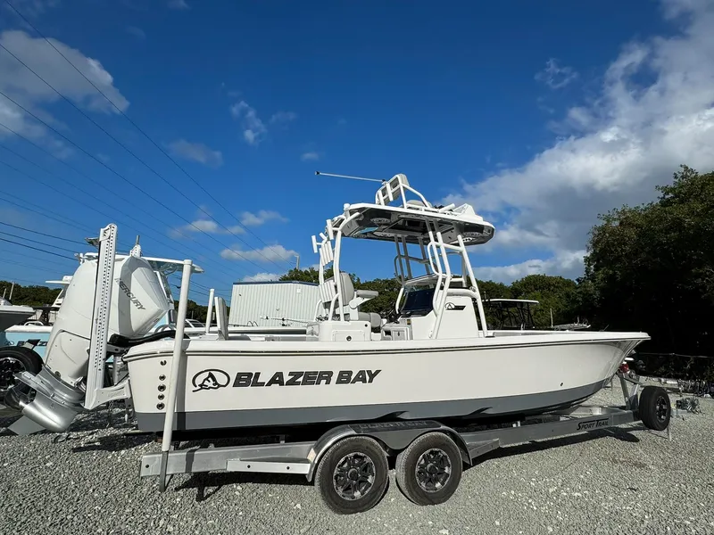 Slide: The Image of 2025 Blazer 2700 Hybrid Bay boat with tower on trailer under blue sky. - 2