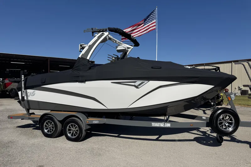 Slide: The Image of 2025 Tigé Z1 boat on trailer with cover, American flag in background. - 18