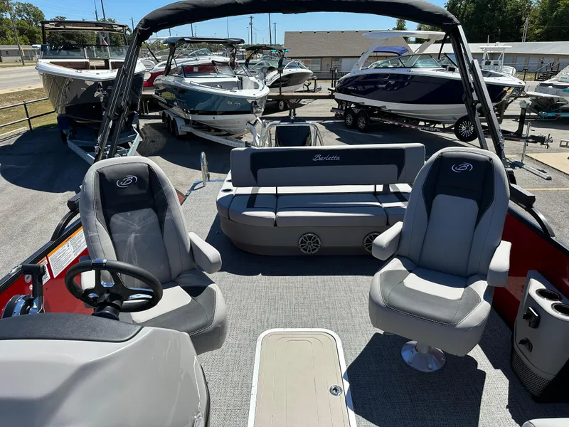 Slide: The Image of 2025 Barletta A24UC boat interior with seating and steering wheel, displayed at a marina. - 26