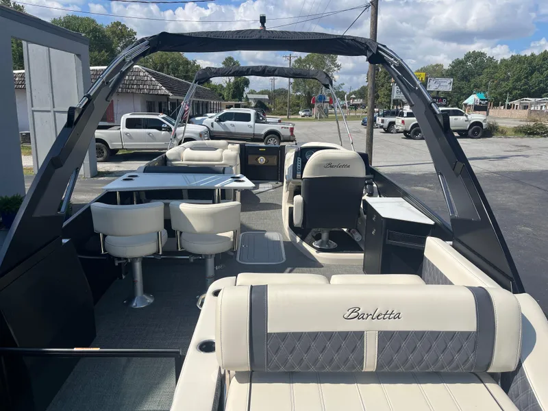 Slide: The Image of 2025 Barletta L25UEA pontoon boat interior with seating and table, parked outdoors. - 10
