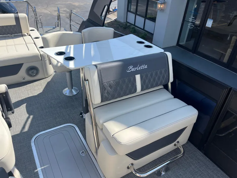 Slide: The Image of 2025 Barletta L25UEA boat interior with seating and table, featuring cup holders. - 19