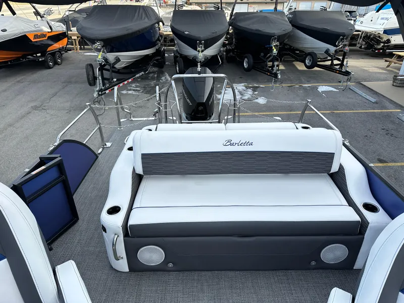 Slide: The Image of 2024 Barletta X23UC pontoon boat interior with seating, docked among covered boats. - 22