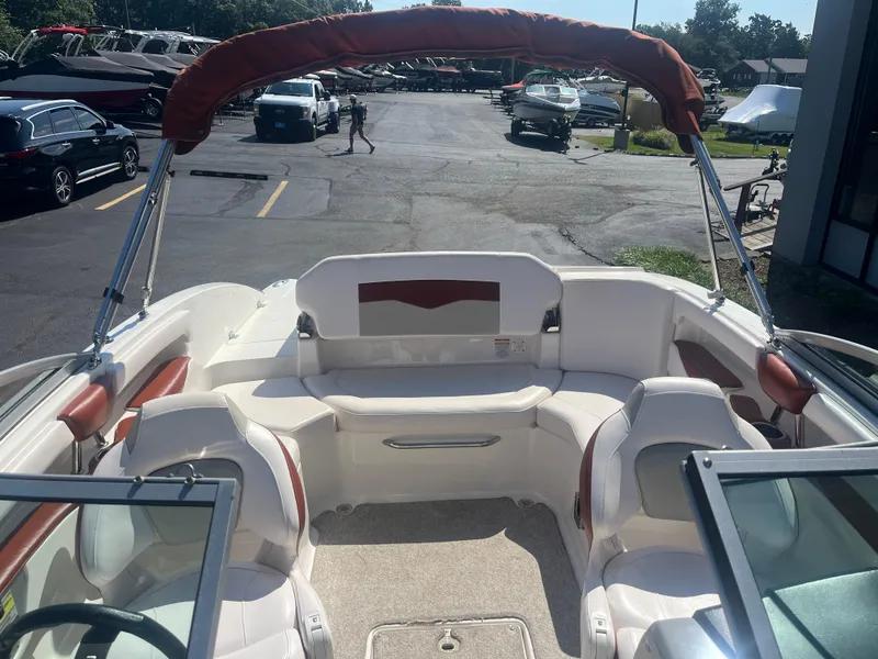 Slide: The Image of 2010 Chaparral 226 boat interior with seating and canopy in a parking lot. - 12