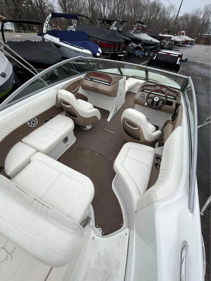 Slide: The Image of 2007 Cobalt 232 boat interior with white seating and dashboard, parked among other boats. - 4