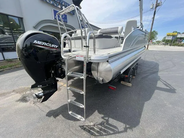 Slide: The Image of 2024 Harris 230CX pontoon boat with Mercury engine, rear view, parked outdoors. - 19