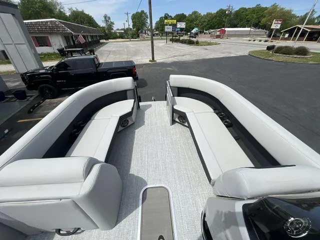 Slide: The Image of 2024 Harris 230CX pontoon boat with spacious seating, parked in a lot. - 26