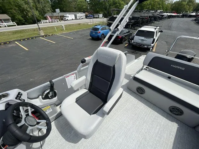 Slide: The Image of 2024 Harris 230CX boat interior with steering wheel and seating, parked in a lot. - 28