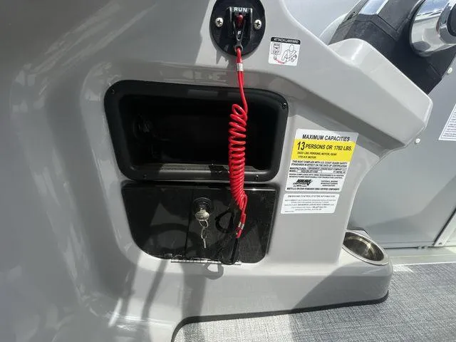 Slide: The Image of 2024 Harris 230CX boat dashboard with safety key and capacity label. - 5