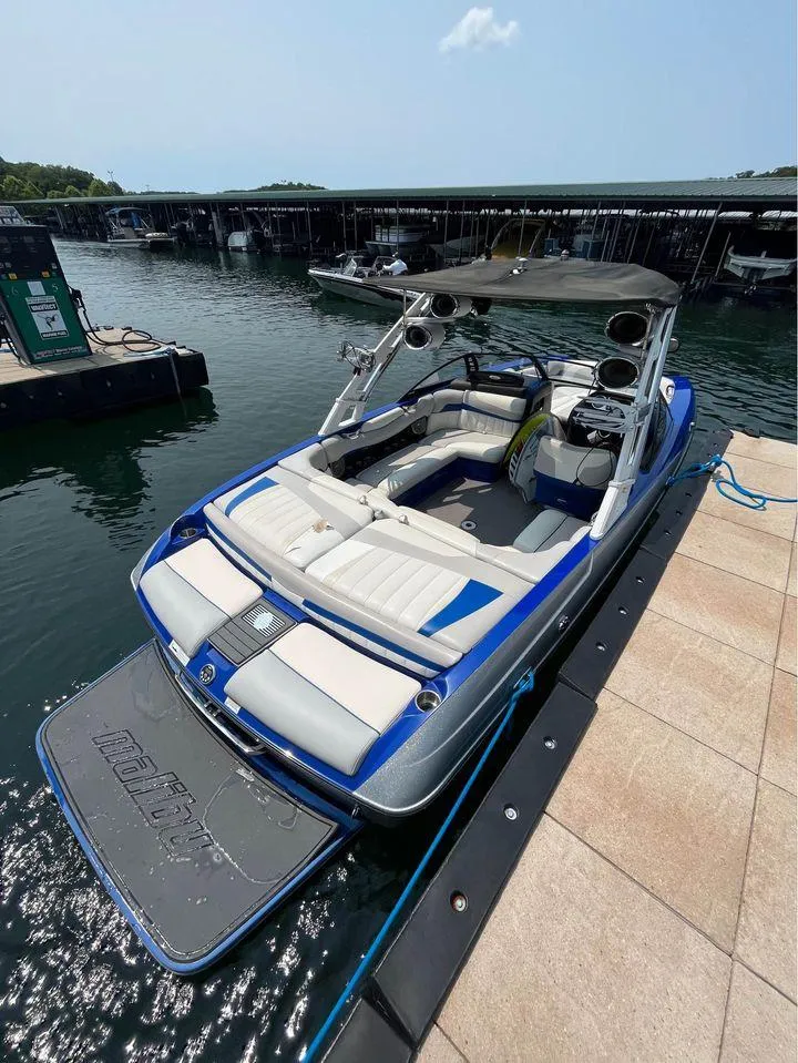 Slide: The Image of 2012 Malibu 22 MXZ boat docked at marina, featuring sleek design and spacious seating. - 3