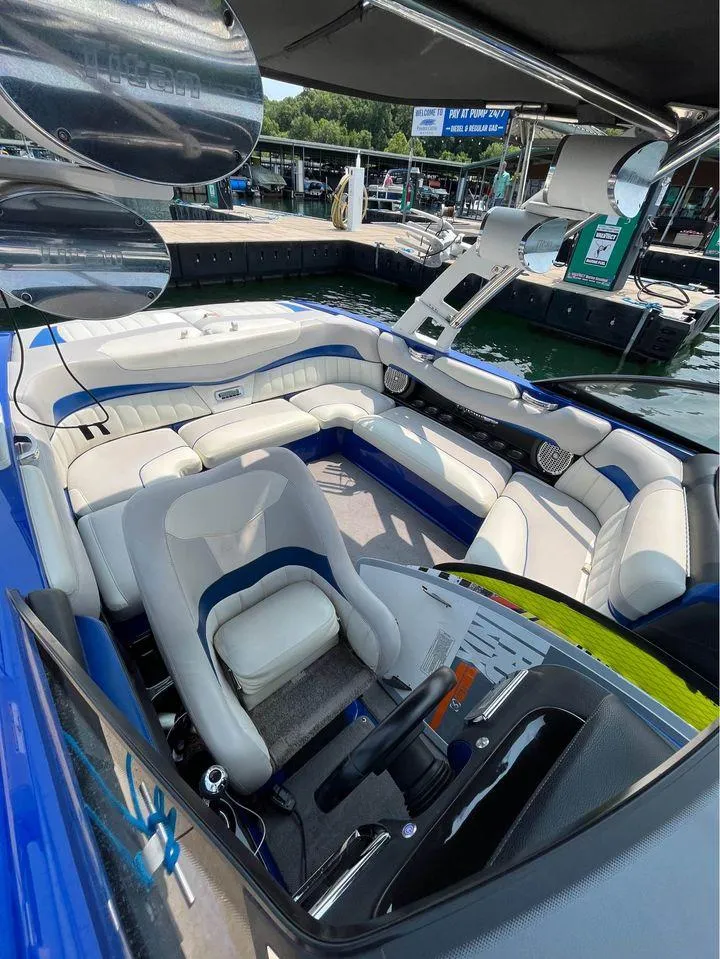 Slide: The Image of 2012 Malibu 22 MXZ boat interior with white and blue seating, docked at marina. - 5