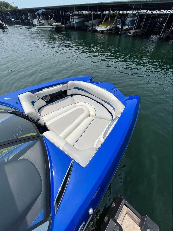 Slide: The Image of Blue 2012 Malibu 22 MXZ boat with white seating, docked on calm water. - 6
