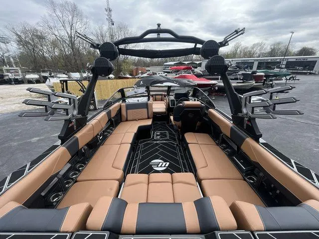 Slide: The Image of 2024 Malibu 23LSV boat interior with tan and black seating, sleek design, and spacious layout. - 11