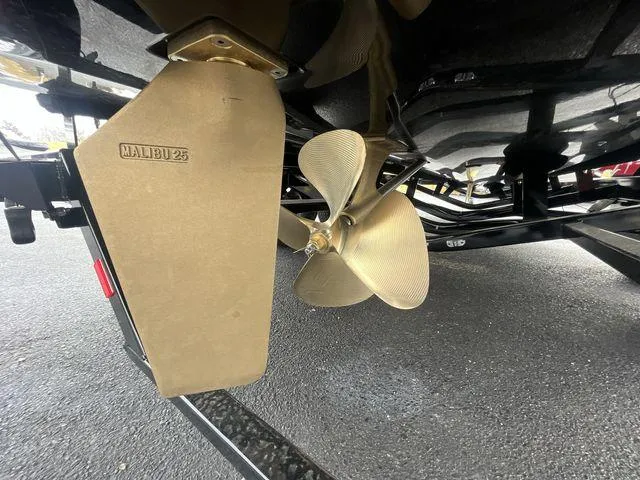 Slide: The Image of 2024 Malibu 23LSV boat propeller and rudder detail on a trailer. - 15