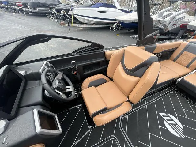 Slide: The Image of 2024 Malibu 23LSV boat interior with tan and black seating, modern dashboard, and steering wheel. - 19