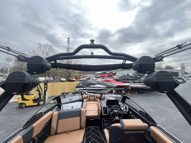 Slide: The Image of 2024 Malibu 23LSV boat interior with tan seats and modern dashboard under cloudy sky. - 7