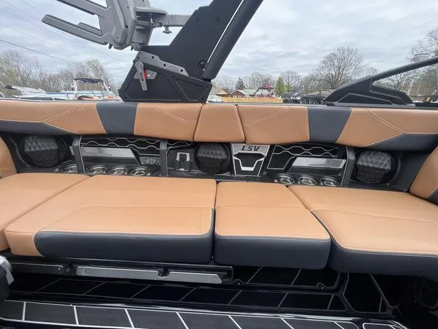 Slide: The Image of 2024 Malibu 23LSV boat interior with tan and black seating, cup holders, and speakers. - 8