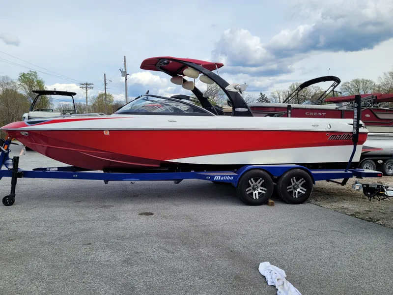 Slide: The Image of 2007 Malibu 247 Wakesetter boat on trailer, red and white design, parked outdoors. - 1