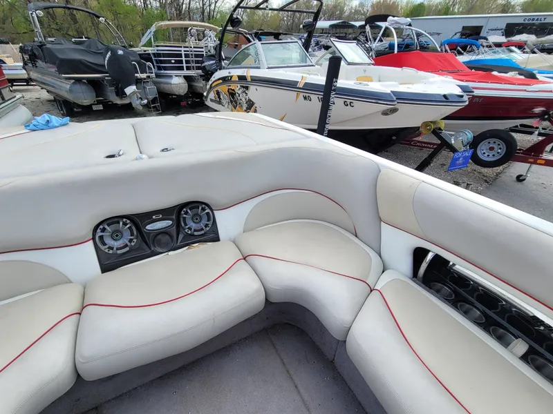 Slide: The Image of 2007 Malibu 247 Wakesetter interior with beige seating and audio system, surrounded by boats. - 10