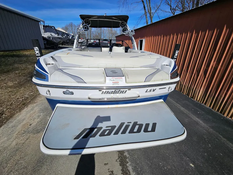 Slide: The Image of 2011 Malibu W247LSV boat with swim platform, parked outdoors. - 3
