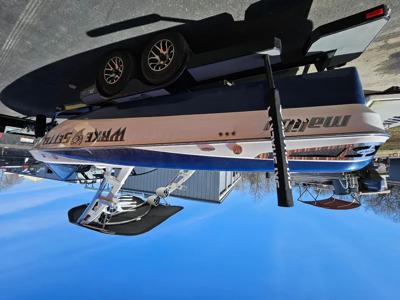 Slide: The Image of 2011 Malibu W247LSV boat on trailer under clear blue sky. - 4