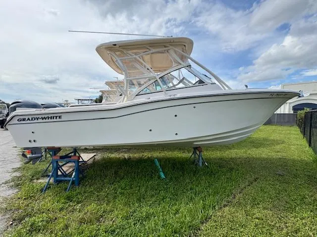 Slide: The Image of 2022 Grady-White Freedom 255 boat on grass, side view under cloudy sky. - 0