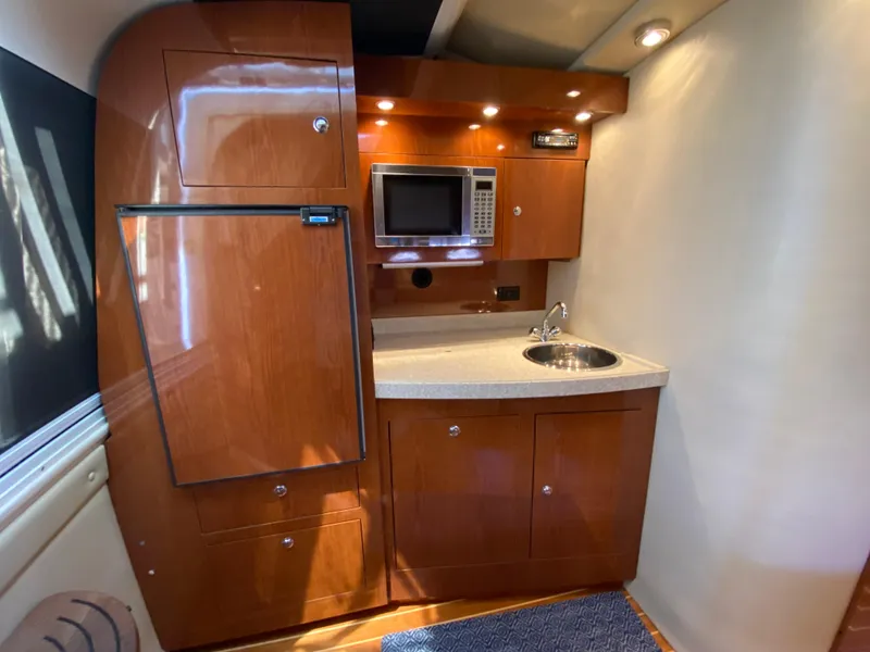 Slide: The Image of 2006 Regal 3560 Commodore yacht kitchen with wood cabinetry, microwave, and sink. - 22