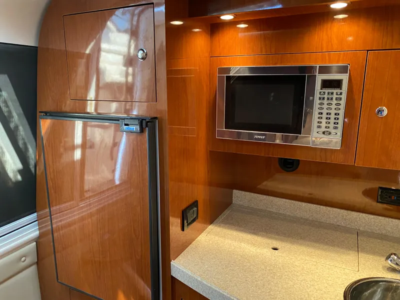 Slide: The Image of 2006 Regal 3560 Commodore yacht kitchen with microwave and wood cabinetry. - 23