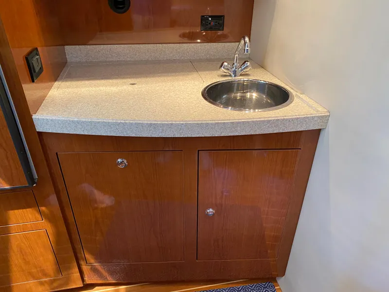 Slide: The Image of 2006 Regal 3560 Commodore yacht kitchenette with sink and wooden cabinetry. - 24