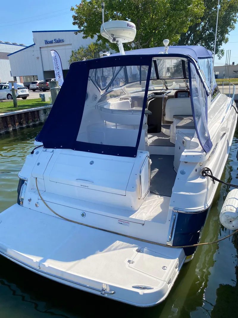 Slide: The Image of 2006 Regal 3560 Commodore boat docked at marina, featuring blue canopy and spacious deck. - 8